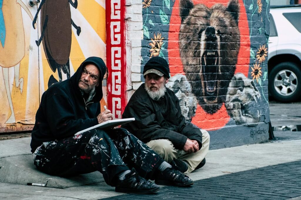 Two Men Sitting on Sidewalk