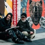 Two Men Sitting on Sidewalk